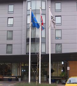 tall white aluminium hotel flagpole with UK flag, close-up of bespoke hotel logo flag