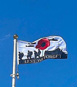 lest we forget joint forces flag flying from a flagpole on a sunny day