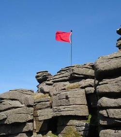 red warning flag flying on cliff top