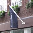 Wall mounted aluminium flag pole on a shop front
