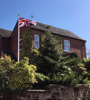 Classic fibreglass flagpole installed in a garden with a Union Jack flag flying
