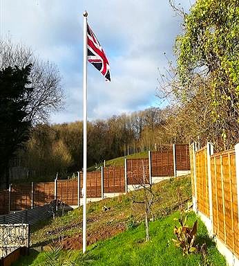 classic aluminium flagpole flying a union jack flag in a garden